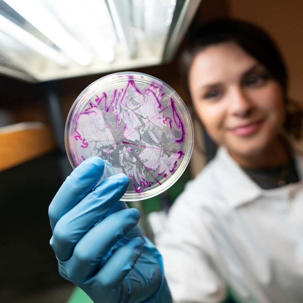Woman holding petri dish with purple growth