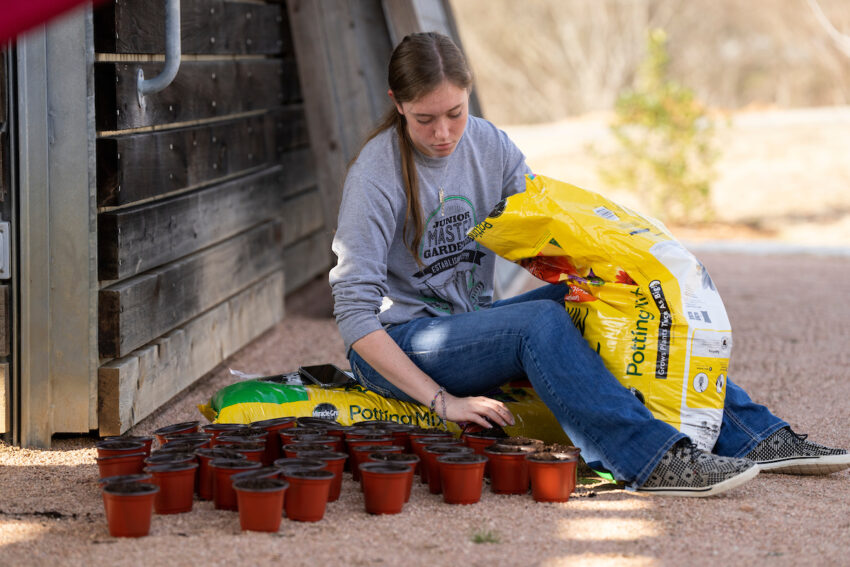 Teen girl adding soil to planters