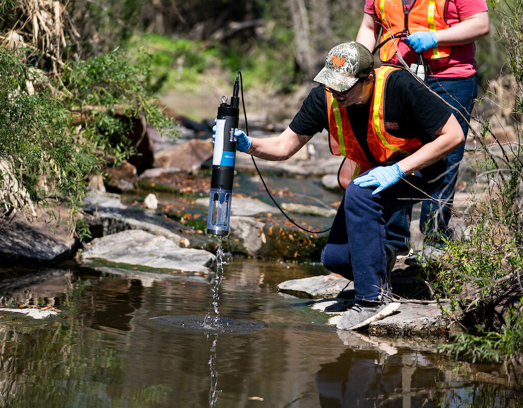 2 students performing a water test in a stream