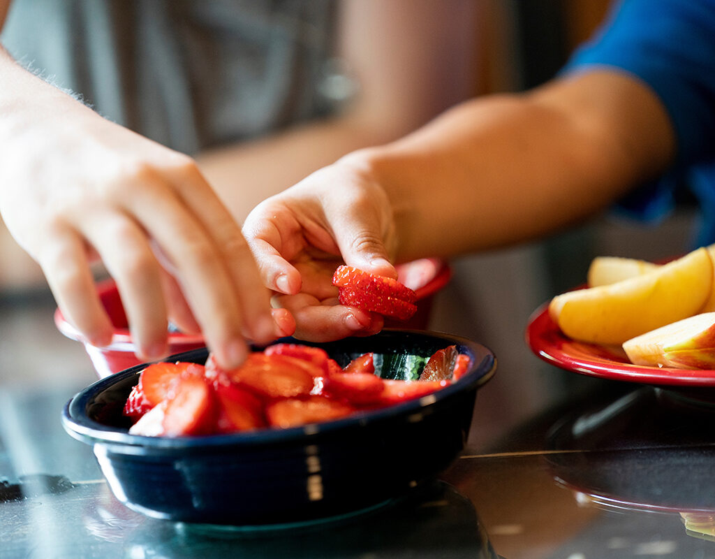 Hands grabbing strawberries from a bowl