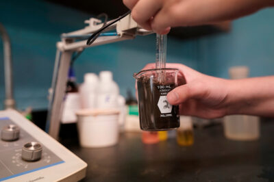 Hands testing a soil sample in a beaker