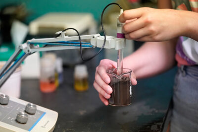 Hands testing a soil sample in a beaker