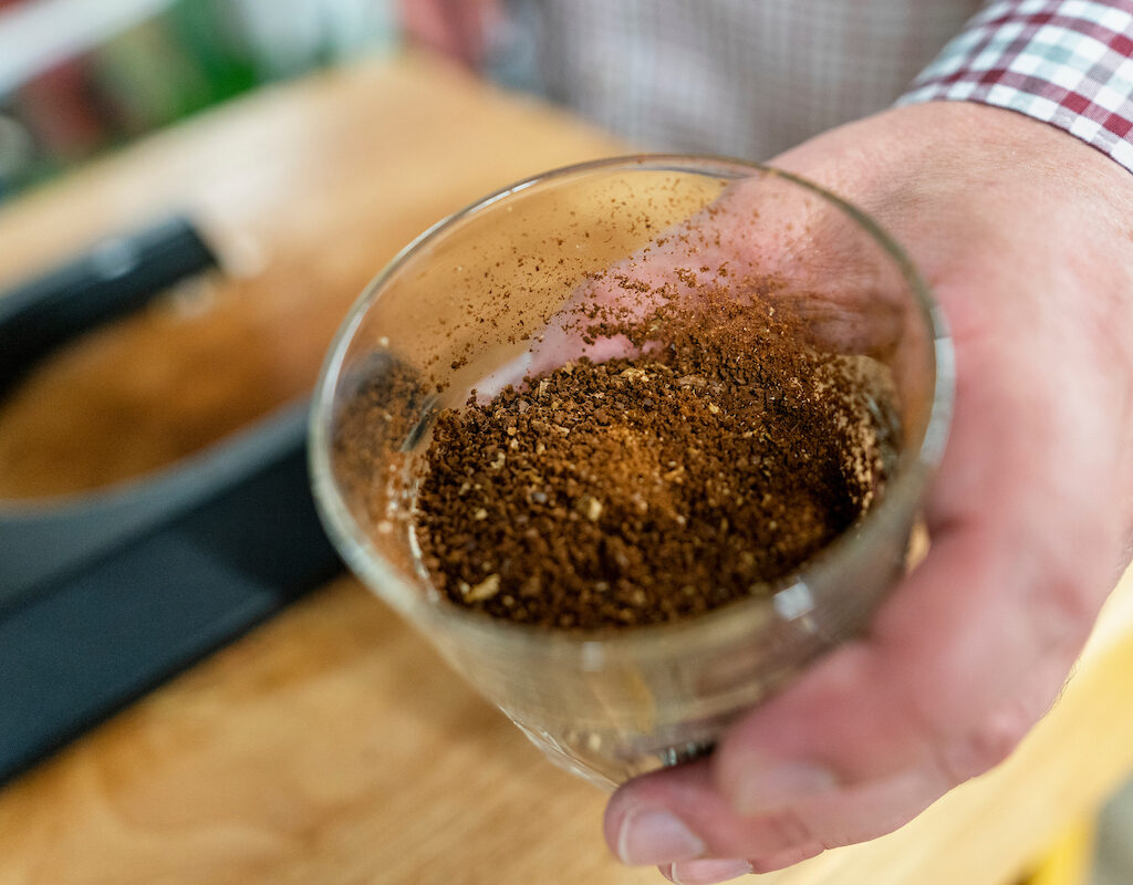 hand holding a glass with ground coffee