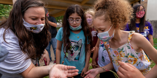 A volunteer showing a garden bug to children