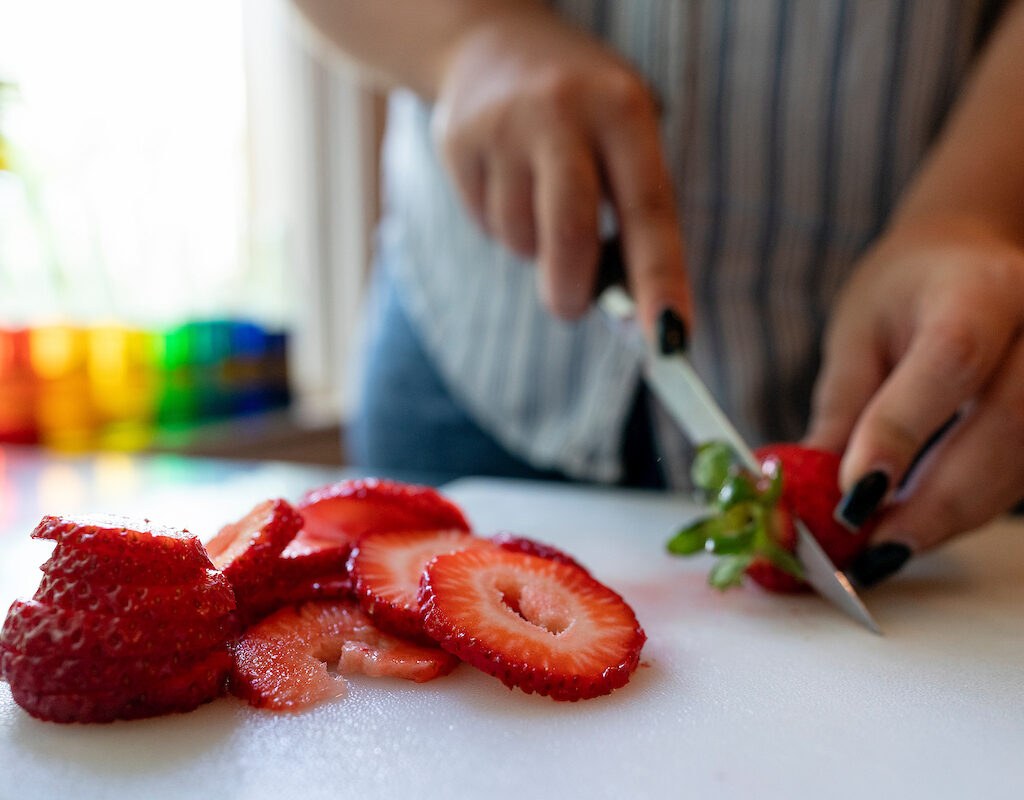 hands chopping a strawberry