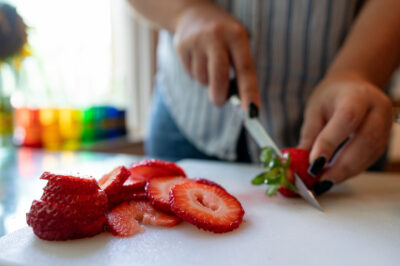 hands chopping a strawberry