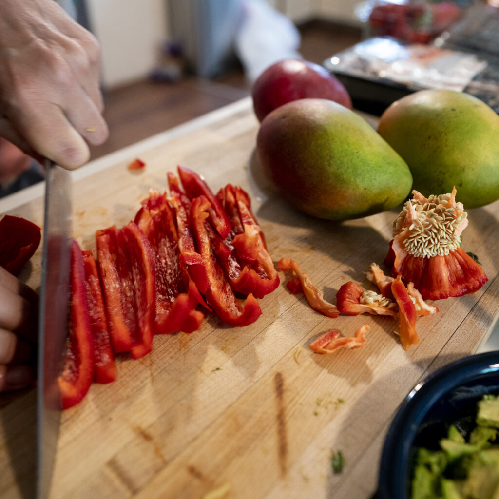hands cutting up a red pepper