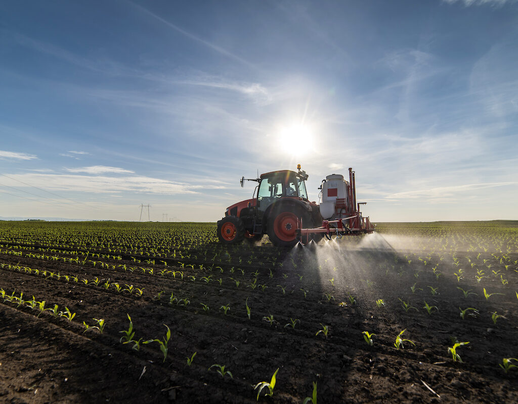 Tractor applying pesticide to crops in a field