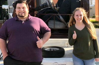 employees standing in front of a vehicle giving a thumbs-up