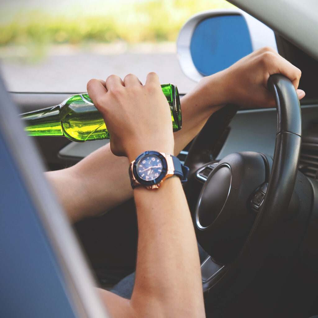 hands holding a bottle behind a steering wheel